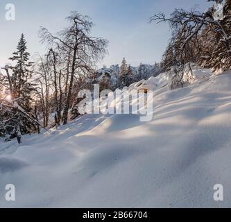 Idillische Berglandschaft mit Schneeverwehungen und schneebedeckten Bäumen Stockfoto