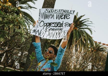 Málaga, SPANIEN - 8. MÄRZ 2020: Schwarze Frau, die während des feministischen Streiks in Málaga, Spanien, am 8. März 2020 ein Banner mit Waffengewalt zeigt. Stockfoto