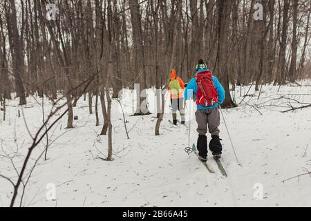 Gruppenläufer mit Rucksäcken gehen und trainieren im Winterwald Stockfoto