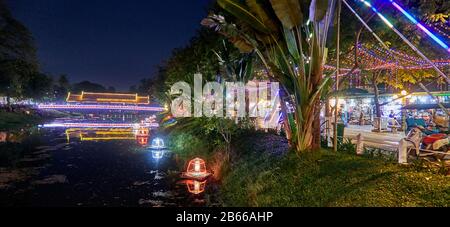 Eine traditionelle Holzbrücke über den Siem Reap River, die zum Siem Reap Art Center Night Market führt, leuchtet und ist in Neonlampen dekoriert. Auf dem Markt werden Souvenirs, Kunstwerke und Schnitzereien verkauft. Der Markt Stockfoto