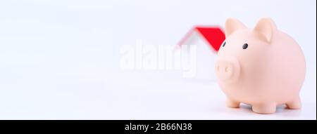 Finanzklage - Piggy Bank, wunderschönes rot-weißes Holzhausmodell auf weißem Hintergrund, spart Geld beim Kauf von Versicherungen, Nahaufnahme, Kopierplatz. Stockfoto