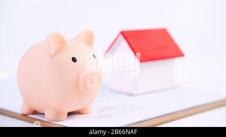 Finanzklage - Piggy Bank, wunderschönes rot-weißes Holzhausmodell auf weißem Hintergrund, spart Geld beim Kauf von Versicherungen, Nahaufnahme, Kopierplatz. Stockfoto