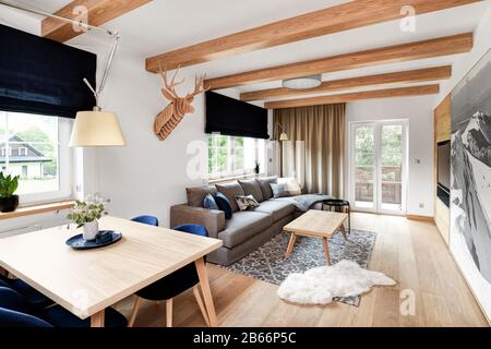 Holzeinhausung moderner Luxusapartments in den Bergen, Wohnzimmer und Küche Stockfoto