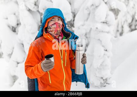 Man gießt heißen Tee aus der Thermoskanne im Winter Wald Stockfoto