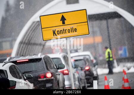 März 2020, Österreich, Gries Am Brenner: An einer Leitstelle der Brennerautobahn A13 befindet sich ein Schild mit der Aufschrift "Control", im Hintergrund hat sich eine lange Warteschlange von aus Italien kommenden Fahrzeugen gebildet. Österreich führt Stichprobenkontrollen für Reisende an der Grenze ein, um eine weitere Verbreitung des neuartigen Coronavirus zu verhindern. Foto: Matthias Balk / dpa Stockfoto