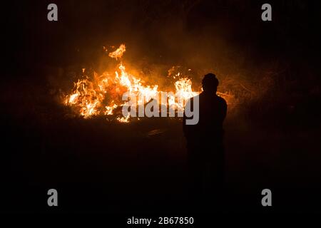 Mann verbrennt Trockenrasen auf einem frei werdenden Grundstück, Gikuyu In Der Nähe von Rennbahn, Ngong Road, Nairobi, Kenia, 11. März 2019 Stockfoto