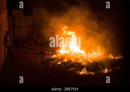 Mann verbrennt Trockenrasen auf einem frei werdenden Grundstück, Gikuyu In Der Nähe von Rennbahn, Ngong Road, Nairobi, Kenia, 11. März 2019 Stockfoto