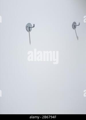 Zwei Kleiderhaken an einer weißen Wand mit Platz für Kopien Stockfoto
