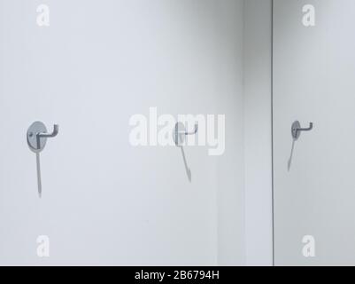 Zwei Kleiderhaken an einer weißen Wand mit Platz für Kopien Stockfoto