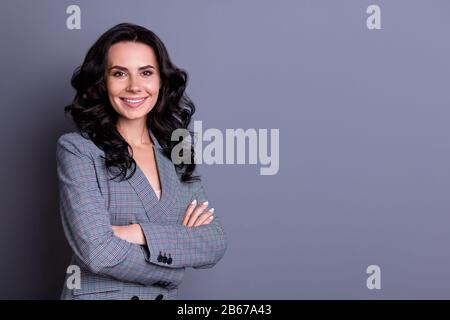 Gedrehtes Foto einer schönen Frau, die ihre Hände überquere und dabei den Anzug über grauem Hintergrund isoliert ansah Stockfoto