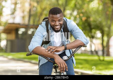 Glücklicher Afroamerikanischer Mann, Der Auf Dem Fahrrad Sitzt Und Sich Vor Der Kamera Posiert Stockfoto
