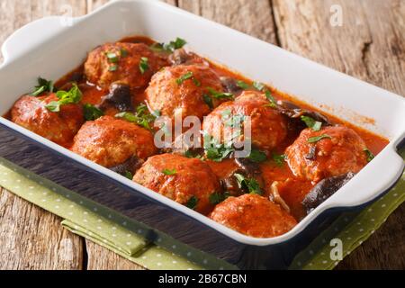 Würzige Fleischbällchen mit Wildpilzen in Tomatensauce in einer Backform auf dem Tisch. Horizontal Stockfoto