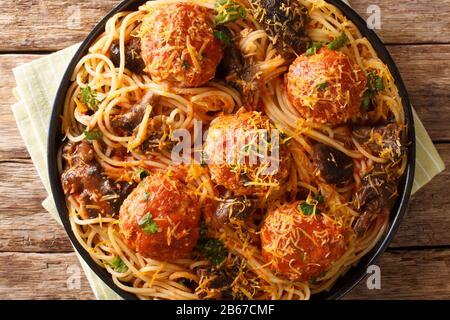 Leckere italienische Spaghetti mit Fleischbällchen und Pilzsauce in einem Teller auf dem Tisch. Horizontale Draufsicht von oben Stockfoto