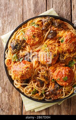 Spaghetti-Pasta mit Fleischbällchen, Pilzen und Cheddar-Käse in einem Teller auf dem Tisch. Vertikale Draufsicht von oben Stockfoto
