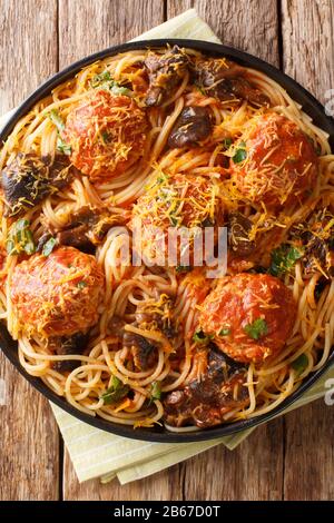 Herzhaftes italienisches Spaghetti-Mittagessen, serviert mit Fleischbällchen, Käse und Pilzen in einem Teller auf dem Tisch. Vertikale Draufsicht von oben Stockfoto