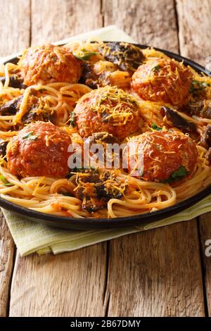 Italienische Fleischbällchen mit einer Beilage aus Spaghetti mit Pilzen und Cheddarkäse in einer Platte auf dem Tisch. Vertikal Stockfoto