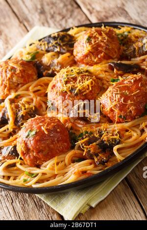 Spaghetti-Pasta mit Fleischbällchen, Pilzen und Cheddar-Käse in einem Teller auf dem Tisch. Vertikal Stockfoto