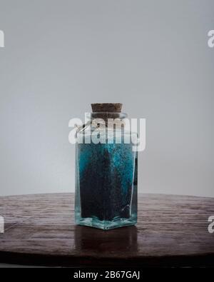 Edle Flasche mit blauen Badesalzen für entspannende Spa-Behandlungen mit weißem Hintergrund und Tageslicht Stockfoto