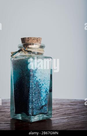 Edle Flasche mit blauen Badesalzen für entspannende Spa-Behandlungen mit weißem Hintergrund und Tageslicht Stockfoto