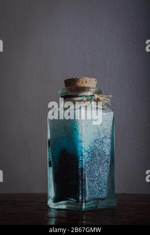 Edle Flasche mit blauen Badesalzen für entspannende Spa-Behandlungen mit weißem Hintergrund und Tageslicht Stockfoto