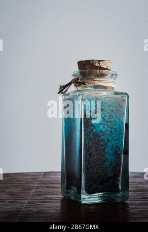 Edle Flasche mit blauen Badesalzen für entspannende Spa-Behandlungen mit weißem Hintergrund und Tageslicht Stockfoto