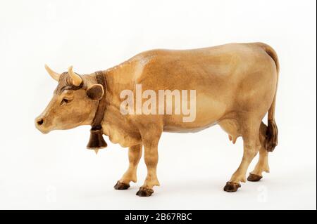 Holzfigürung einer Kuh mit einer Glocke am Hals isoliert auf weißem Grund. Stockfoto