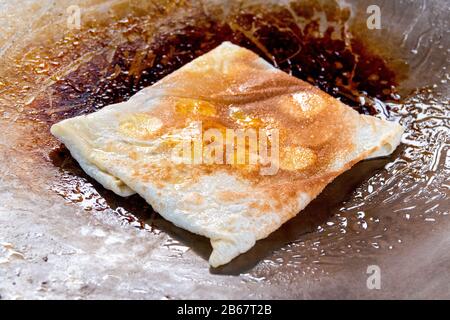 Kochen des traditionellen thailändischen Roti-Gulay (Bananenpfannkuchen) in einer Pfanne Stockfoto