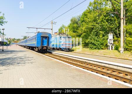 Der alte blaue Zug verlässt das Bahnhaus am Bahnhof. Stockfoto