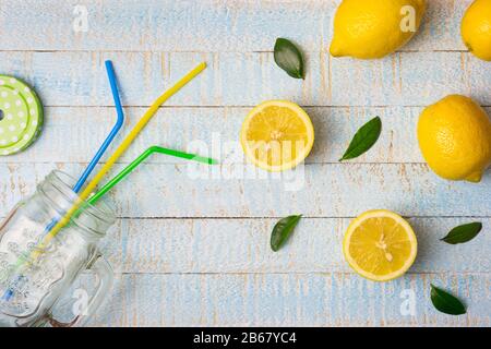 Flache Laienzusammensetzung mit Smoothie-Glas und frischen Zitronen auf hellblauem Holzhintergrund. Kopierbereich, Draufsicht. Stockfoto