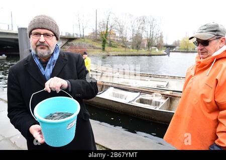 10. März 2020, Brandenburg, Potsdam: Axel Vogel (Bündnis 90/die Grünen), Brandenburger Minister für Landwirtschaft, Umwelt und Klimaschutz, hält einen Eimer mit Jugendlichen Aalen im Potsdamer Hafen, bevor er sie in die Havel bringt. Die Bevorratung der Havelgewässer mit insgesamt 300.000 jungen Aalen ist Teil eines langfristigen Pilotprojekts zur Koordination der Aalbestockungsmaßnahmen im Land Brandenburg. Foto: Soeren Stache / dpa-Zentralbild / ZB Stockfoto