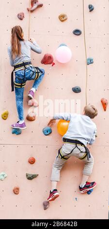 Zwei Kinder klettern auf die bullige künstliche Wand und konkurrieren in Geschwindigkeit und Stärke Stockfoto