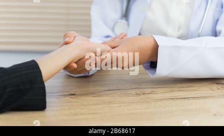 Nahaufnahme eines Arztes, der die Hände des Patienten hält, der grundlegende medizinische Untersuchungen und Diagnosen durchgeführt hat. Ein Arzt untersucht den Patienten im Krankenhaus. Stockfoto