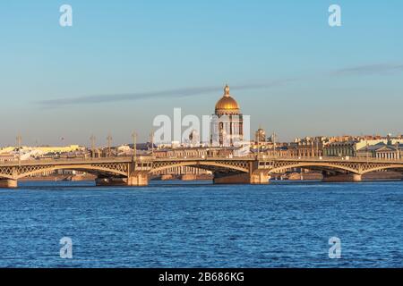 Blick auf die Verkündigungsbrücke über den Fluss Newa und die von der Sonne beleuchtete Kathedrale von St. Isaac in der Stadt Sankt Petersburg Stockfoto