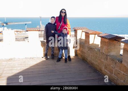 Mutter junge Brunette-Frau mit zwei Söhnen 10 und 4 Jahren auf dem Hintergrund des Meeres Stockfoto