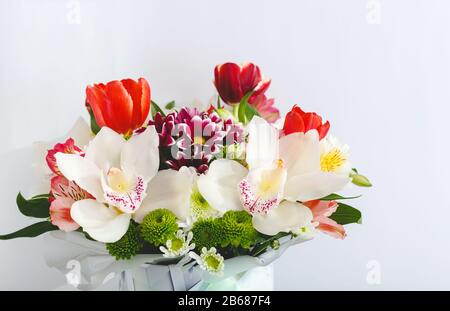 Blumenstrauß mit bunten Frühlingsblumen auf weißem Hintergrund mit Kopierraum. Blumenstrauß aus Tulpen, Orchideen, Chrysanthemen-Blumen für Muttertag, Valentinstag Stockfoto