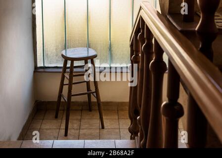 Alter Holzbalkenhocker in einer Holztreppe mit Handgeländer in einem Alten Haus. Inneneinrichtung alter Treppen. Design im Old House mit Barhocker Stockfoto