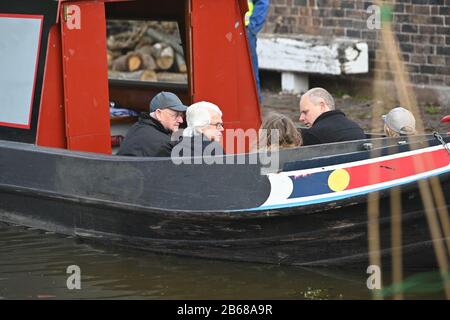 Eine Gruppe von Leuten, die vor einem Schmalboat sitzen und plaudern, während sie auf dem Kanal in Norbury Staffordshire UK entlang fährt Stockfoto