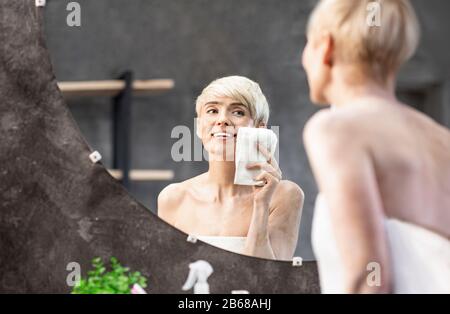 Frau Trocknet Gesicht Mit Handtuch, Das Die Haut Im Bad Pflegt Stockfoto