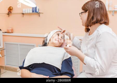 Ein weiblicher Arzt zeigt eine medizinische Vorbereitung auf einen Patienten in einer Klinik für ästhetische Medizin und Kosmetologie Stockfoto