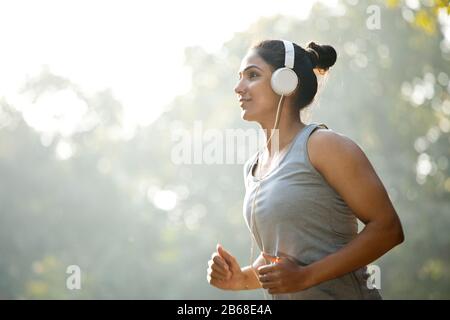 Sportlerin hört Musik und Jogging im Park Stockfoto