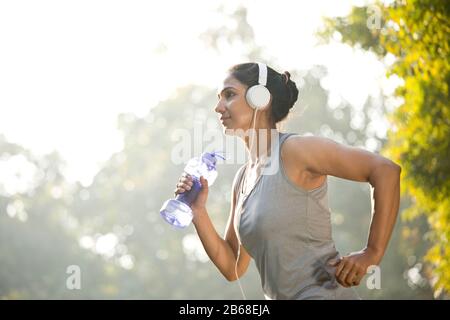 Frau in Sportswear Musik hören beim Sport im Park im Freien Stockfoto