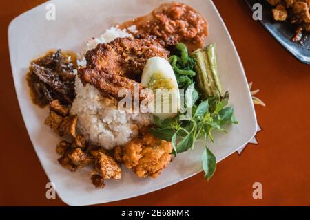 Nasi rumelt mit Hühnerrendang, perkedel tahu, und lalapan sayur Stockfoto