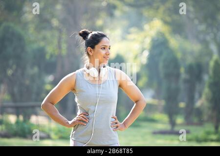 Fit Woman in Sportswear Musikhören auf Kopfhörern im Park Outdoor Stockfoto