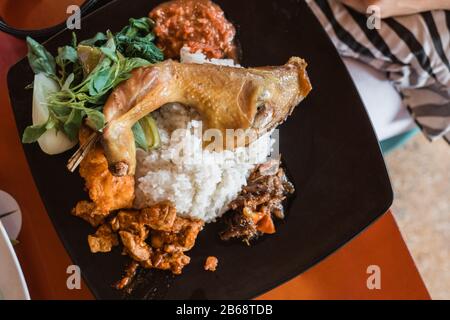 Nasi rammt mit gebratenem Huhn, Lalapan-Sayur und Sambal-Tomat Stockfoto