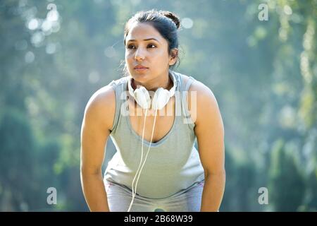 Fit Woman in Sportswear Musikhören auf Kopfhörern im Park Outdoor Stockfoto