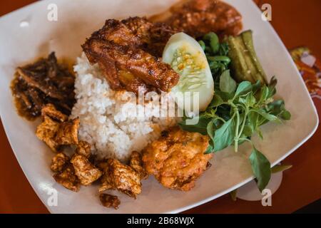 Nasi rumelt mit Hühnerrendang, perkedel tahu, und lalapan sayur Stockfoto