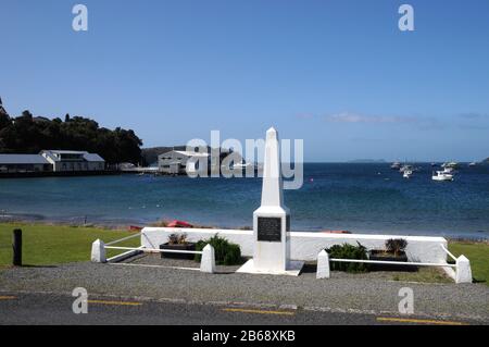 Das Kriegsdenkmal an der Küste von Oban auf Stewart Island, Neuseeland. Der Obelisk blickt über das Meer und die Half Moon Bay. Stockfoto