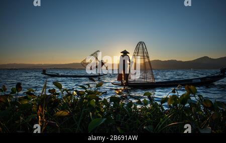 Myanmar, Shan-Staat, Inle Lake Intha-Fischer auf dem Boot bei erstaunlichem Sonnenuntergang Stockfoto