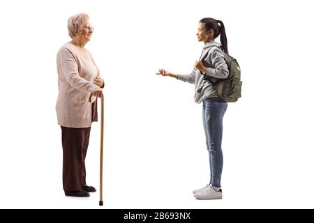 Profilaufnahme einer weiblichen Studentin, die mit einer älteren Frau spricht, mit einem auf weißem Hintergrund isolierten Gehstock Stockfoto