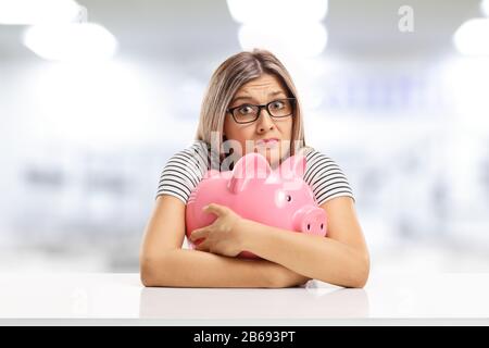 Erschrockene junge Frau umarmt ein Huckepuckchen und sitzt an einem Tisch Stockfoto